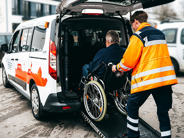 BuFDi schiebt Rollstuhl in Fahrzeug Patientenfahrdienst